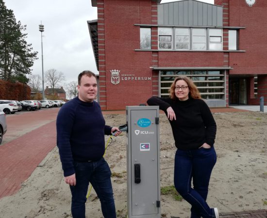 Joost en Louwina bij een laadpaal voor het gemeentehuis van Loppersum