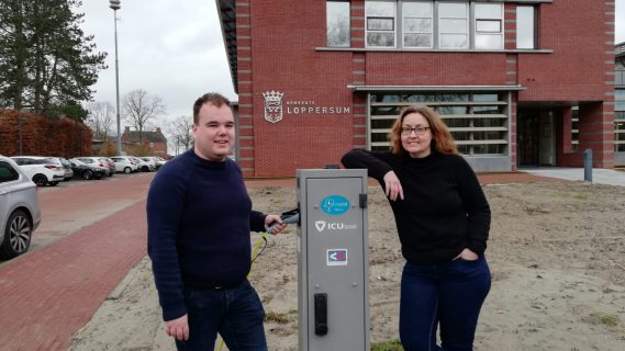 Joost en Louwina bij een laadpaal voor het gemeentehuis van Loppersum