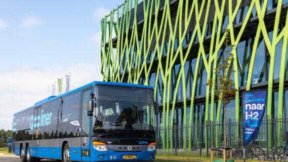 Decoratieve afbeelding van een bus die voor het Hive.Mobility gebouw langsrijdt
