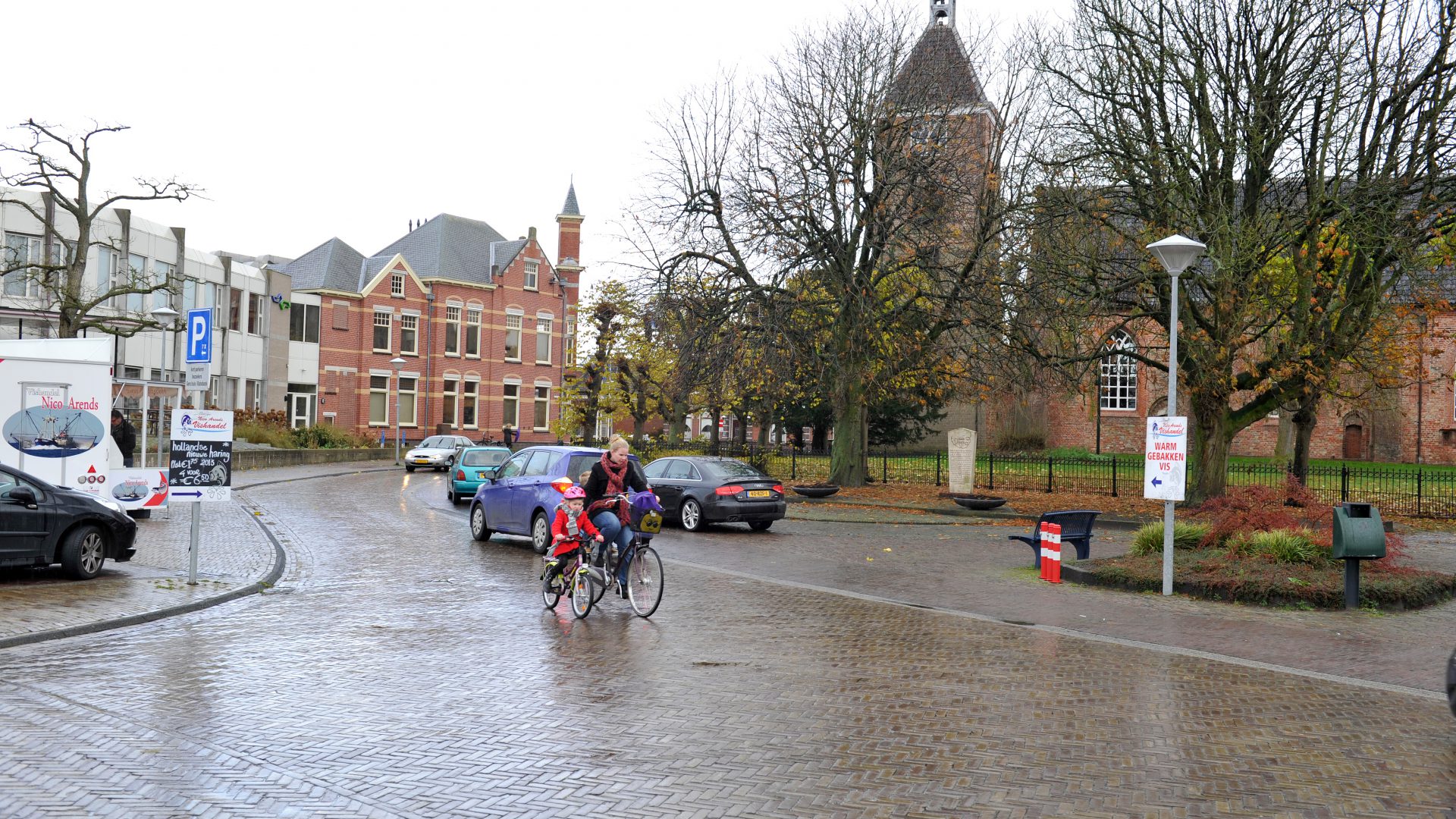 Moeder fietst met kind langs de kerk in Uithuizen.