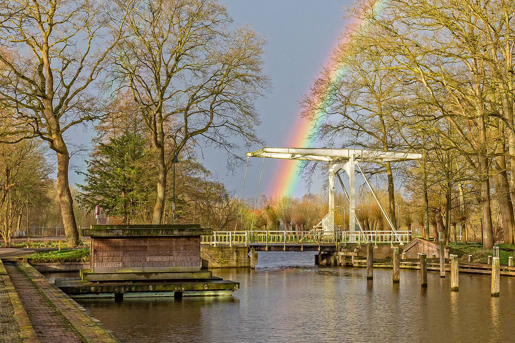 Sfeerbeeld van een bruggetje met regenboog op de achtergrond in Slochteren.