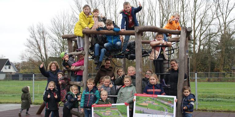 Kinderen in een speeltoestel met bouwtekeningen in hun hand van de nieuwe speeltuin in Zoutkamp.