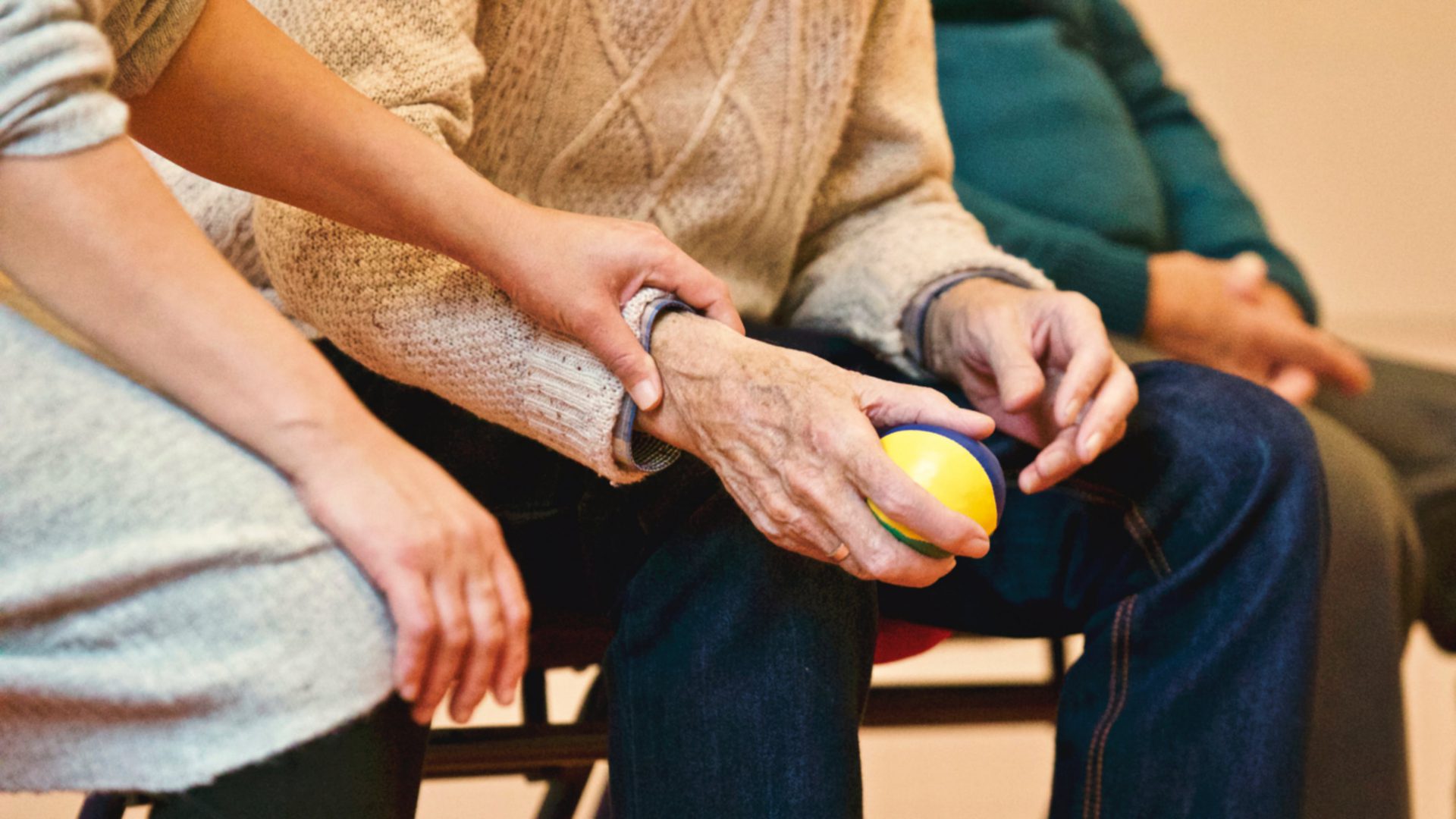 Sfeerafbeedling van een oudere meneer die een balletje vasthoudt, een jongere vrouw legt haar hand geruststellend op zijn pols.