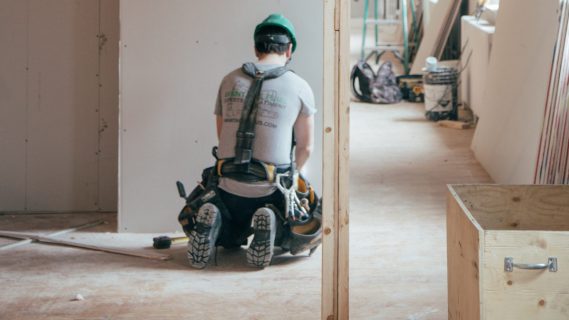 Bouwvakker werkt aan muren in een woning.