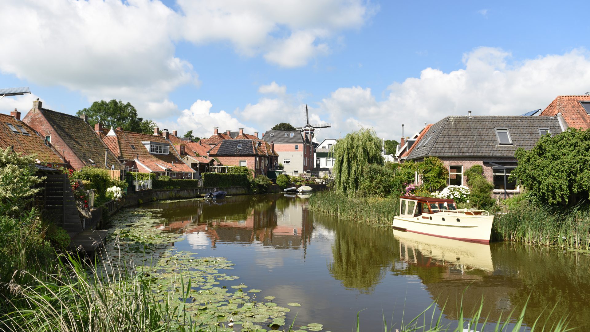 Sfeerbeeld voor het thematisch programma van een plaats in de provincie (Winsum) met huizen aan het water en bootjes in het water