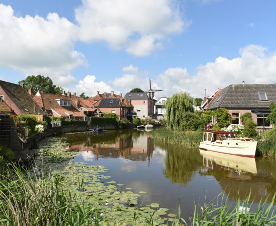 Sfeerbeeld voor het thematisch programma van een plaats in de provincie (Winsum) met huizen aan het water en bootjes in het water