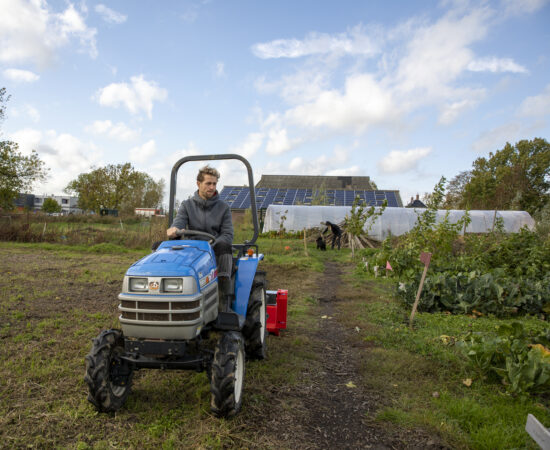 Arjan de Witte op zijn trekker in de zelfsoogsttuin in Ten Boer.