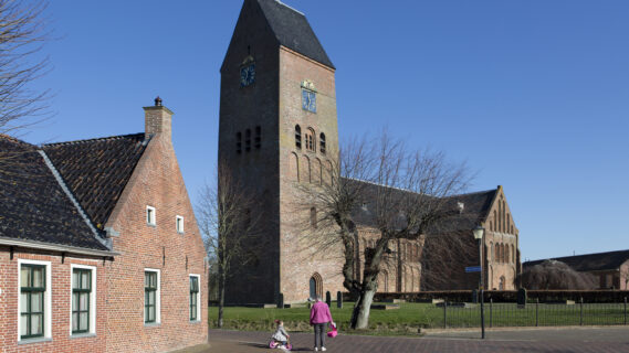 Decoratieve afbeelding van een oma die met haar kleinkind voor de kerk in Zeerijp langsloopt