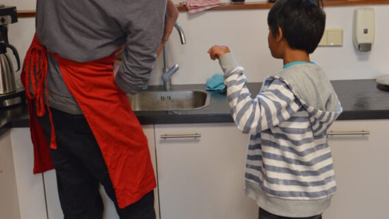 Decoratieve afbeelding van een man die een kind aan het helpen is in de keuken