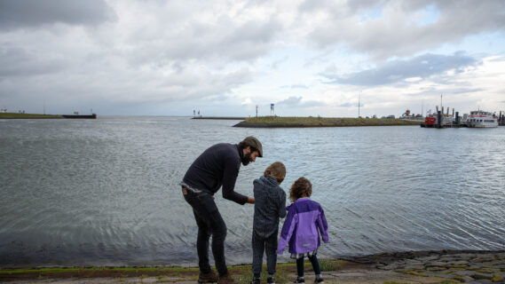 Decoratieve afbeelding van een vader met twee kinderen bij het water in Lauwersoog