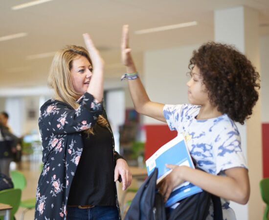 Decoratieve foto van een juf die een leerling een high five geeft op school