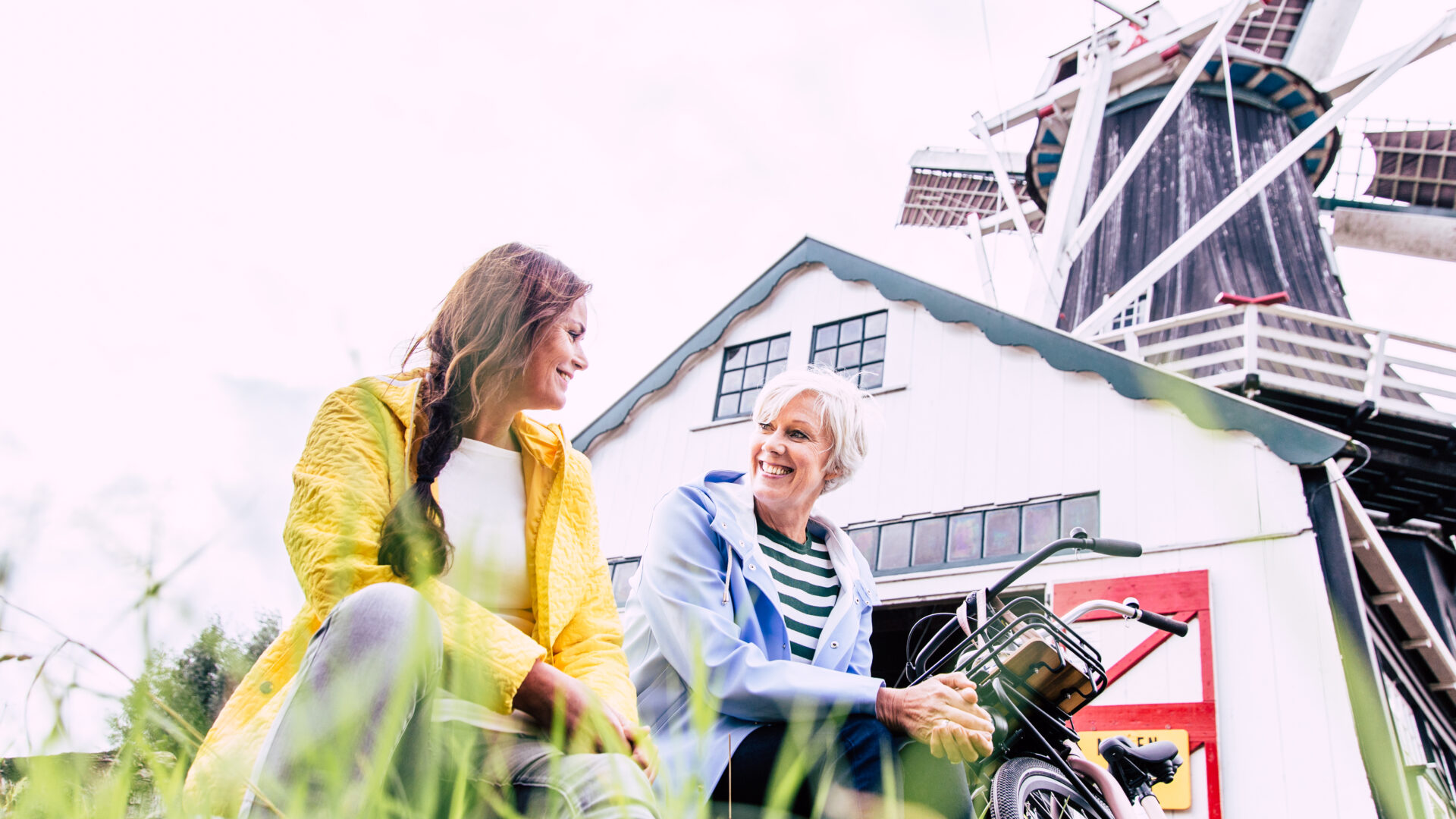 Decoratieve afbeelding van twee vrouwen met hun fiets voor een molen