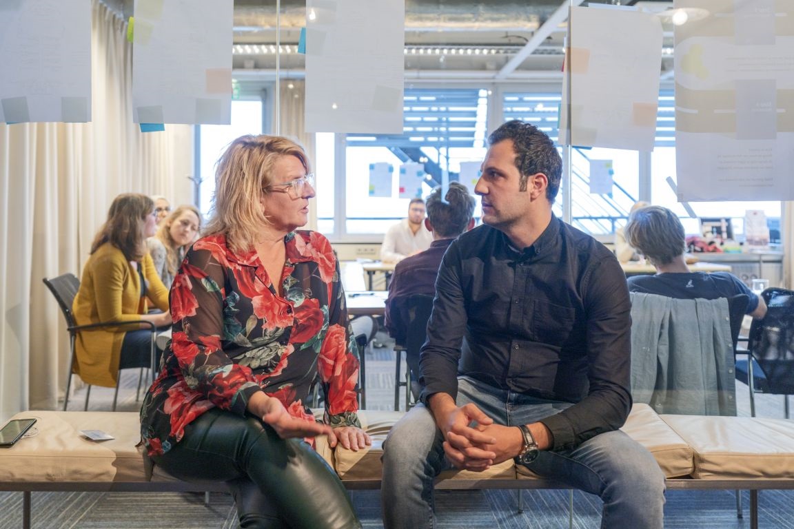 Decoratieve afbeelding van een man en een vrouw die samen op een bankje iets aan het overleggen zijn