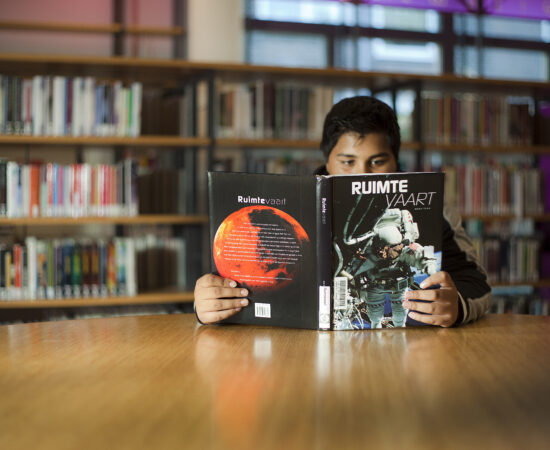 Decoratieve foto van een jongen die in de bibliotheek een boek leest