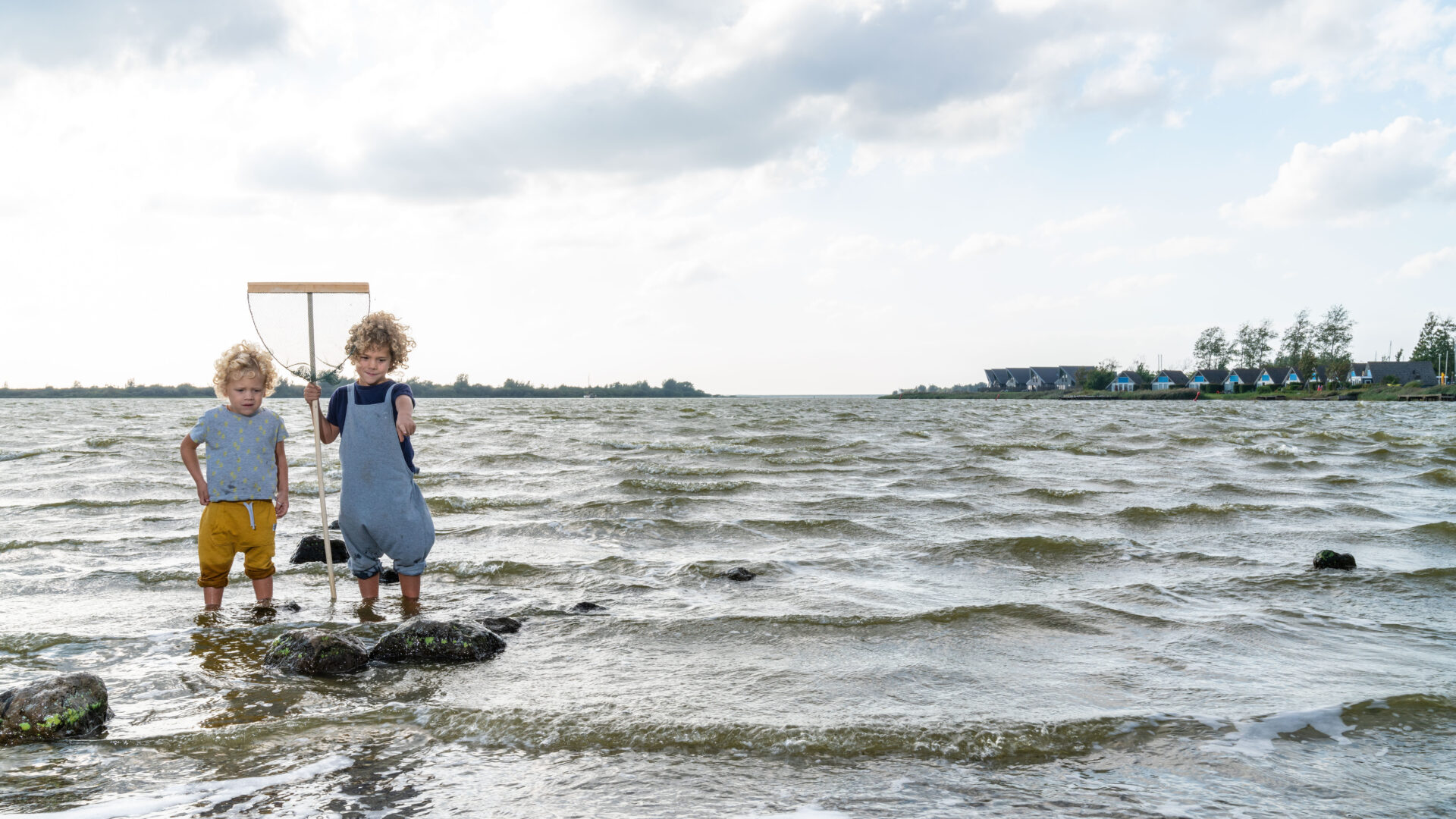 Decoratieve afbeelding van twee kinderen die met een visnetje in het Lauwersmeer staan