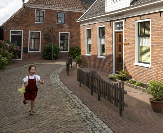 Decoratieve afbeelding van een klein meisje die door de straten van Winsum rent