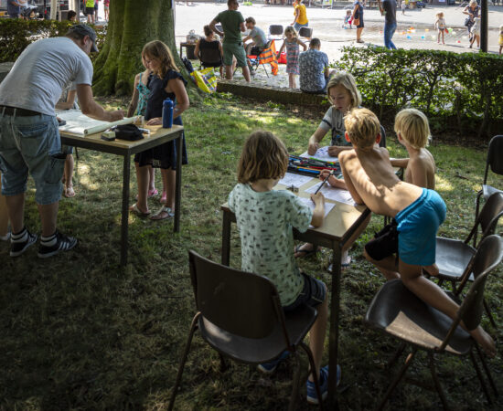 Kinderen tekenen aan schoolbankjes buiten