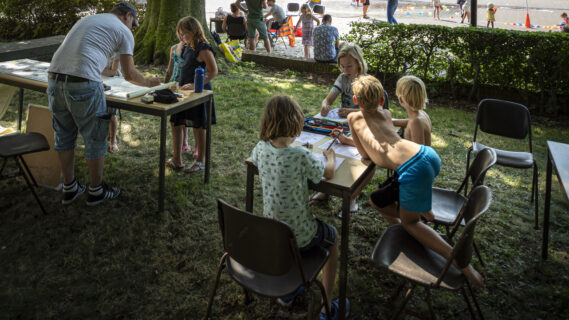Kinderen tekenen aan schoolbankjes buiten