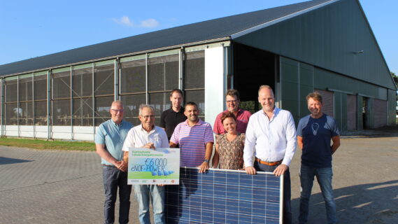 Decoratieve afbeelding van initiatiefnemers van een energiecollectief bij een zonnepaneel en een cheque