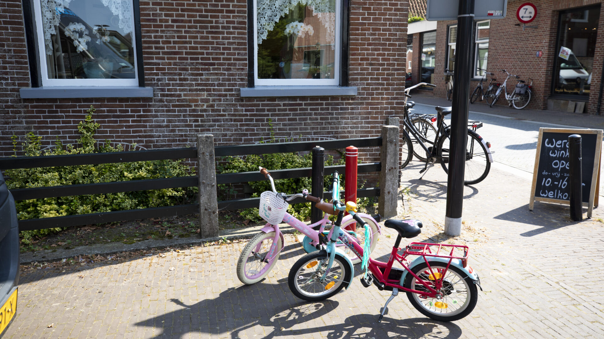 Decoratieve afbeelding van twee kinderfietsjes in Loppersum met een bord van een winkel ernaast