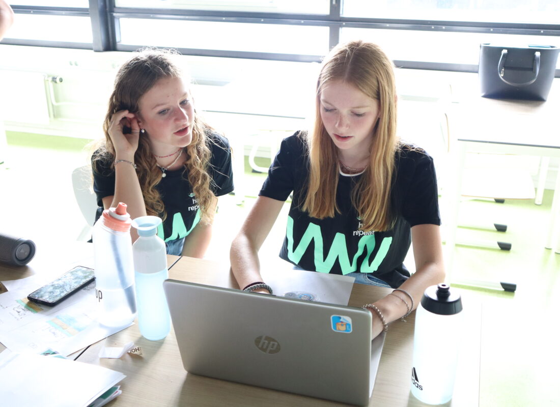 Twee meiden zijn achter hun laptop bezig met het uitwerken van hun idee.