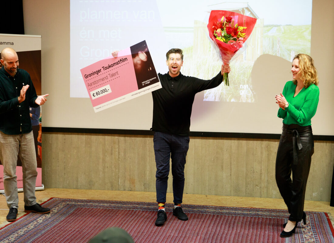 Winnaar Colin Mooijman juicht en houdt bloemen en cheque in de lucht